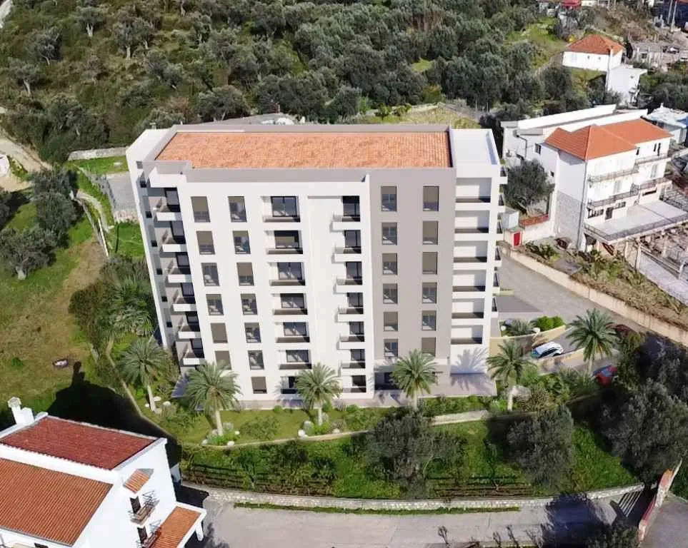 Pogled iz vazduha na stambenu zgradu sa uređenom okolinom i zelenilom.
