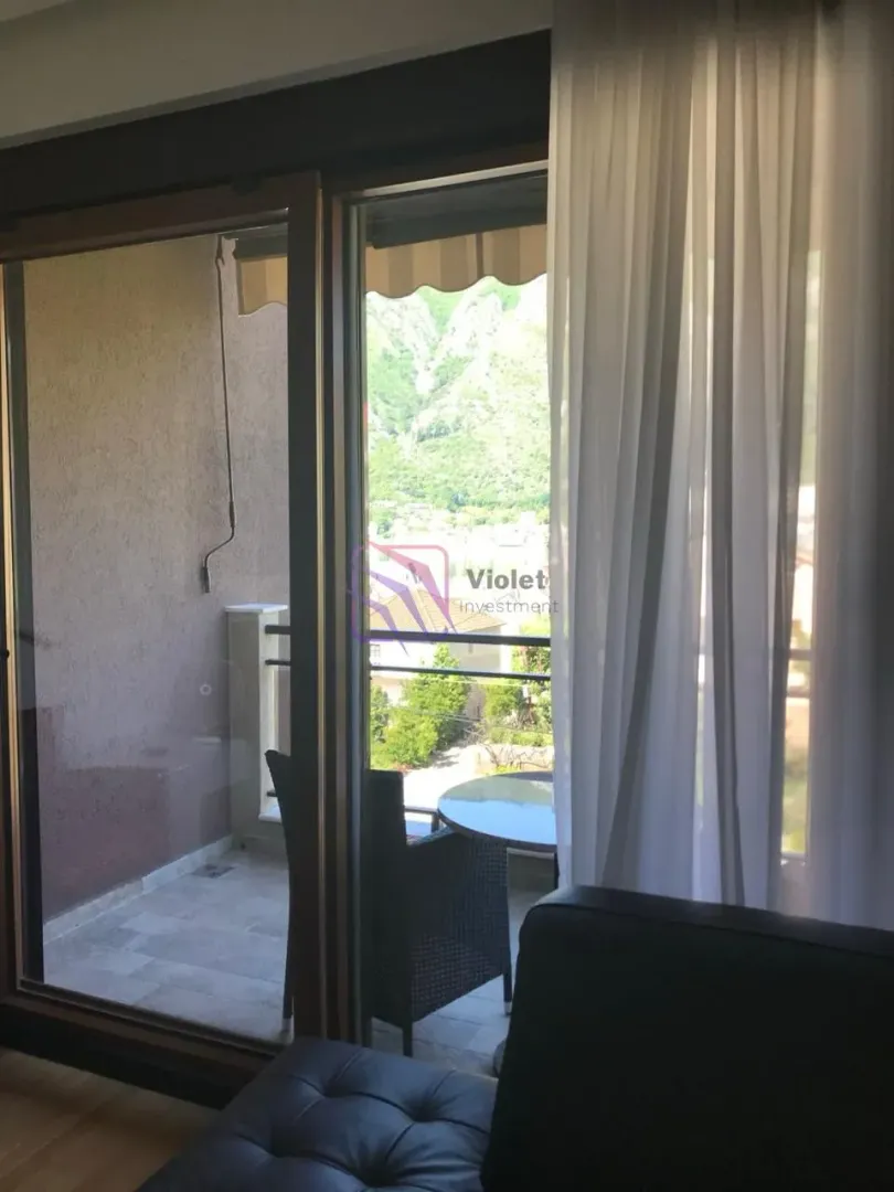 Pogled sa terase na planine i naselje kroz balkonska vrata.