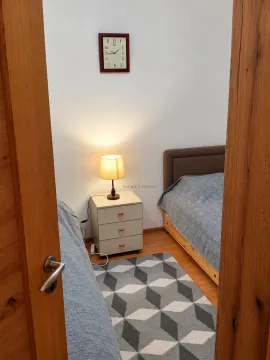 View from the doorway into a bedroom with two beds and a nightstand. - image 7