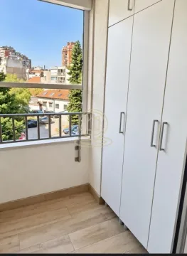 Zastakljeni balkon sa belim ugradnim plakarom i pogledom na grad. - image 14