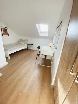 Attic bedroom with a bed, desk, and a roof window. - image 7