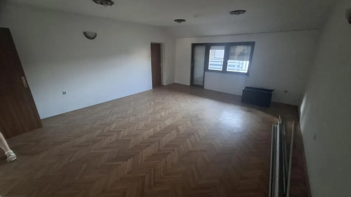Prazna soba sa parketom i prozorom.