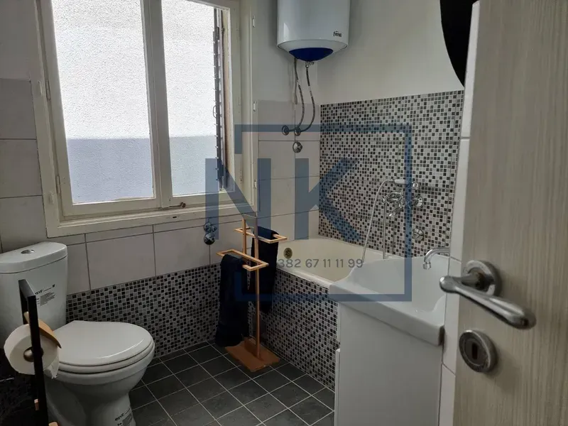 Bathroom equipped with a bathtub, washbasin, toilet, and a window.