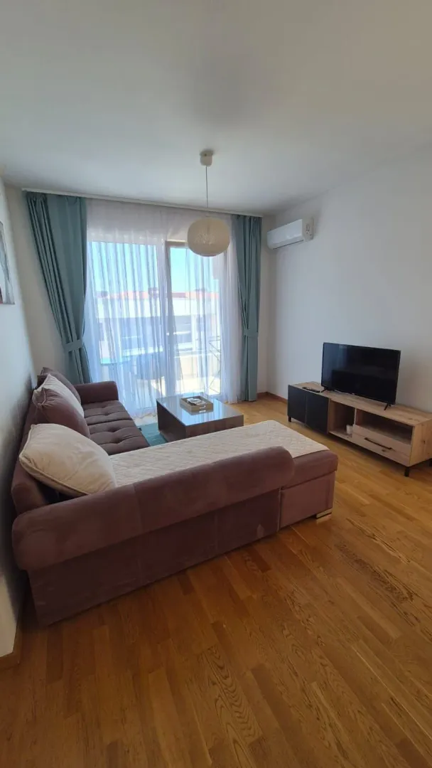 Living room with a sectional sofa, TV unit, and access to the terrace.