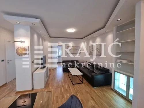 Living room with sofa, TV unit and recessed lighting.