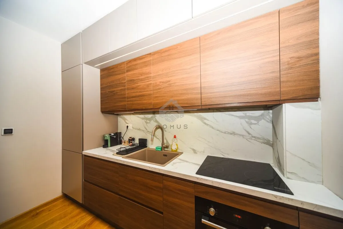 Modern kitchen with wooden cabinetry, marble countertops, and a built-in cooktop.