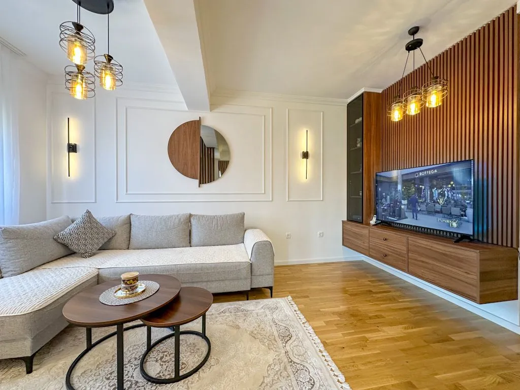 Modern living room with a sofa, wooden wall panels, and a television.