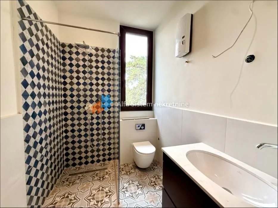 Kupatilo sa tuš kabinom, umivaonikom i ugradnom šoljom.