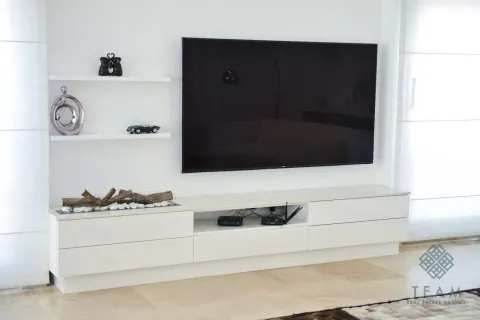Moderna TV komoda sa velikim televizorom i ukrasnim detaljima na zidu. - image 12