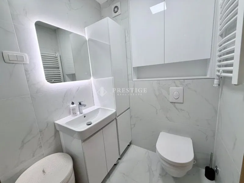 Moderno opremljeno kupatilo sa bijelim pločicama i ugradnim sanitarijama.