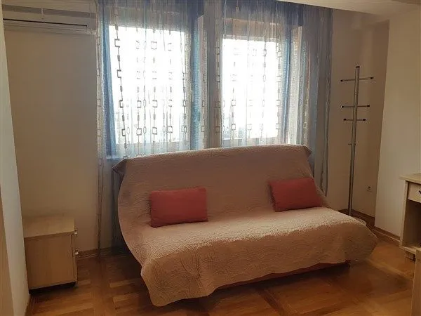 Jednostavna soba sa kaučem i svijetlim prozorima.