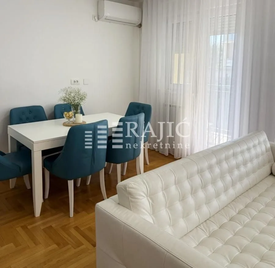Living room with a dining area, sofa set, and white table with chairs.