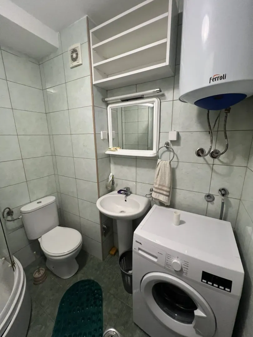 A simple bathroom with a washing machine, sink, and boiler.