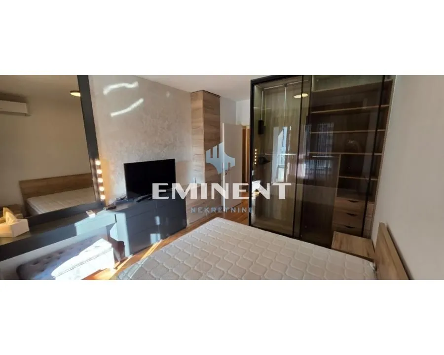 Furnished bedroom with a double bed, wardrobe, and television.
