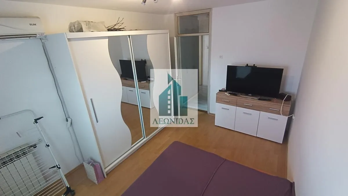 Nameštena spavaća soba sa velikim garderobom, krevetom i televizorom.