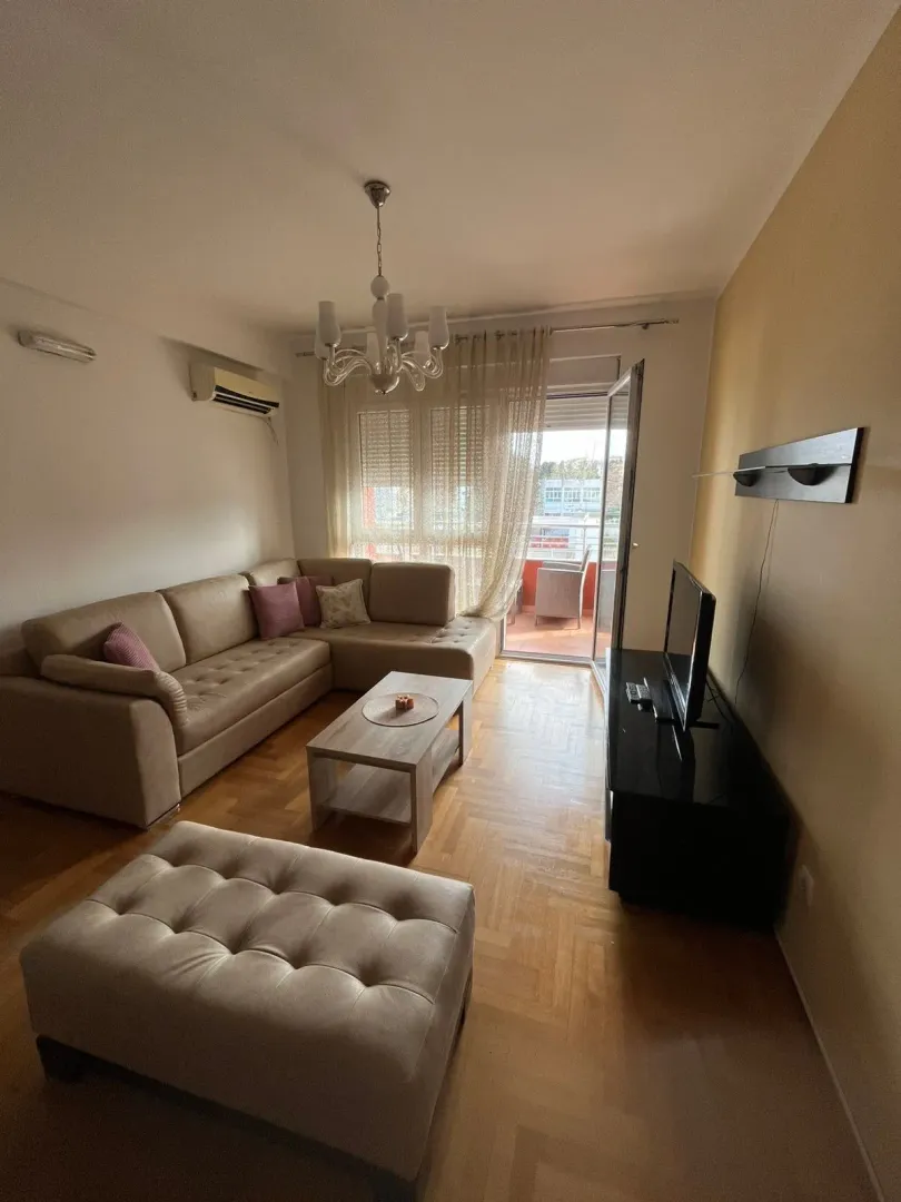 Living room with a sectional sofa, TV, and access to the balcony.
