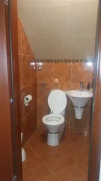 A small attic bathroom with a toilet and sink. - image 8