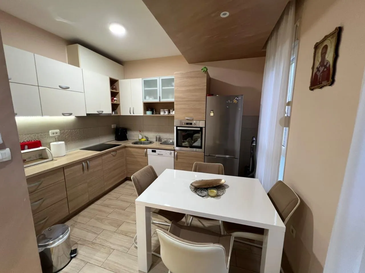 Kitchen equipped with wooden cabinetry and a dining table with white chairs.