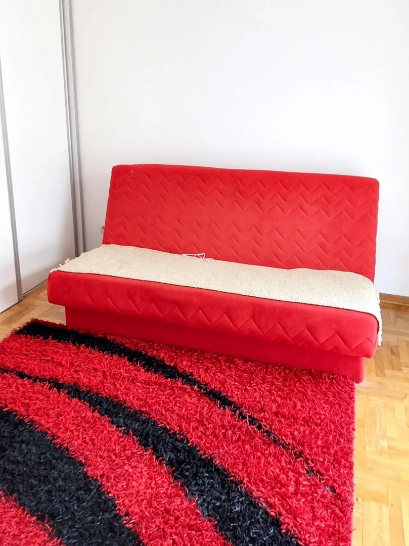 Dnevna soba sa crvenim kaučem i tepihom.