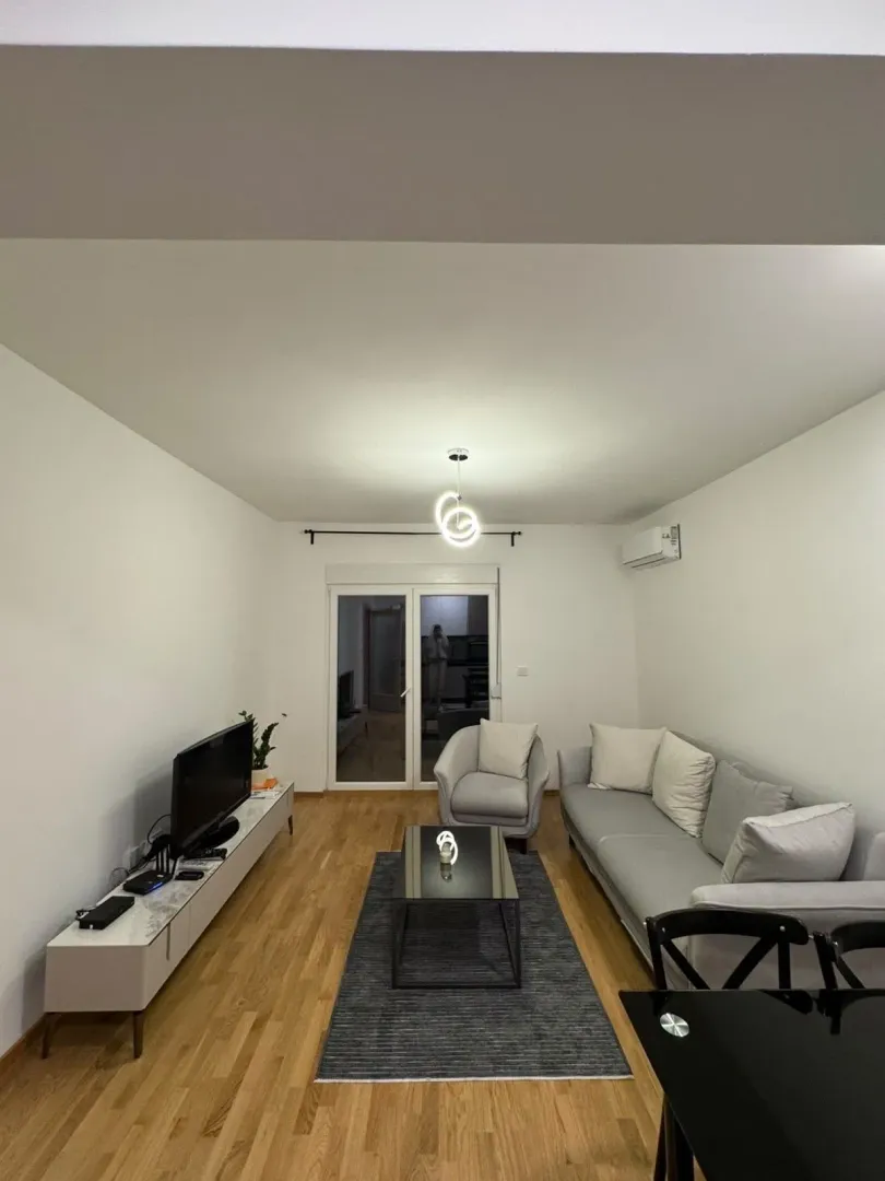 Modern living room with a sofa set, television, and dining table.