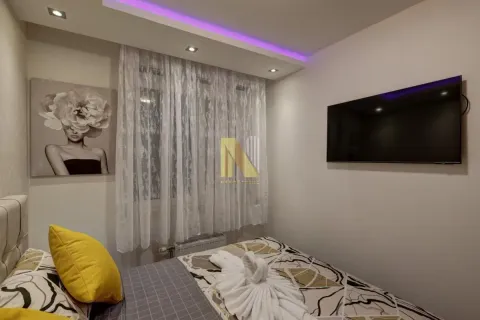 Spavaća soba sa bračnim krevetom, zidnim televizorom i dekorativnim osvetljenjem. - image 10