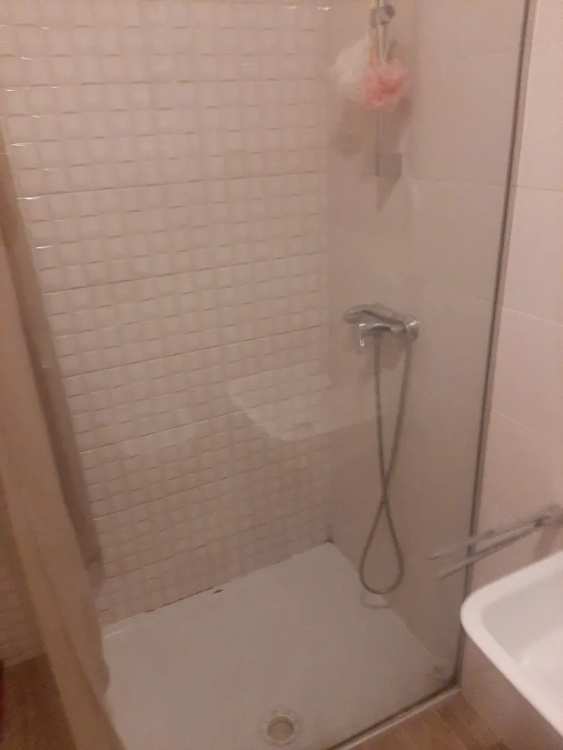 A simple bathroom featuring a shower cabin and light tiles.