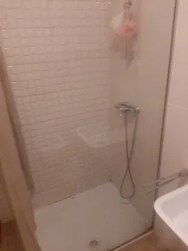 A simple bathroom featuring a shower cabin and light tiles. - image 7