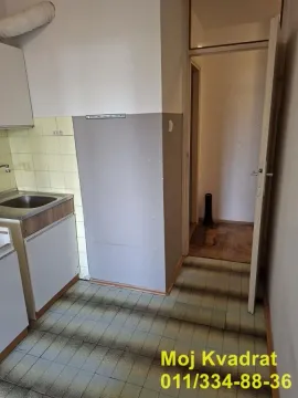 Starija kuhinja sa sudoperom i otvorenim prolazom prema hodniku. - image 3