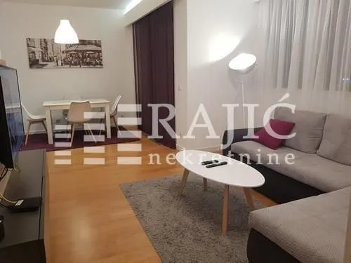 Living room with a sofa, dining table, and hardwood flooring.