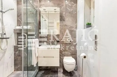 Modernly equipped bathroom with a walk-in shower and marble tiles.