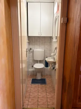Manje kupatilo sa toaletom, umivaonikom i bijelim ormarićem. - image 10