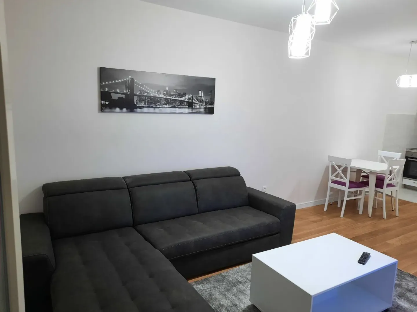 Bright living room featuring a dark sectional sofa and a dining set.
