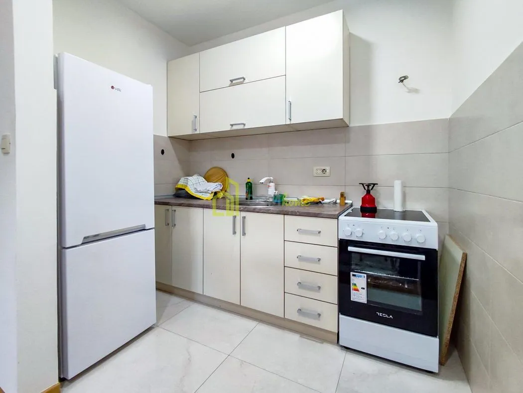 Small kitchen with white cabinets, stove and refrigerator.