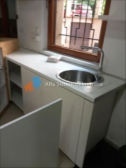 Small kitchen with a sink under the window and white cabinets.