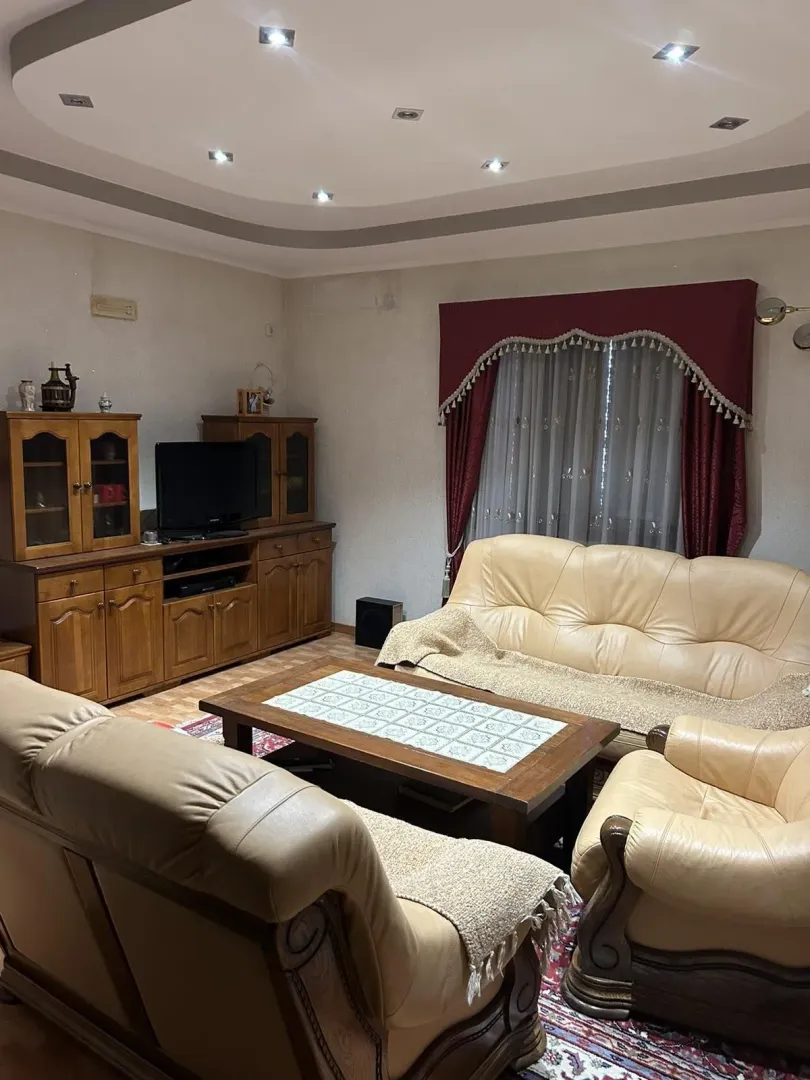 Living room with leather furniture, a wooden coffee table, and a TV cabinet.