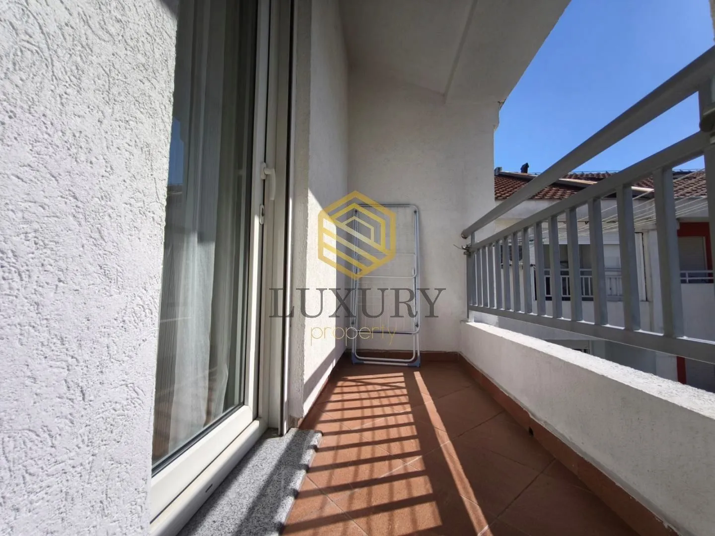 Pogled na prostrani balkon sa ogradom i keramičkim pločicama.