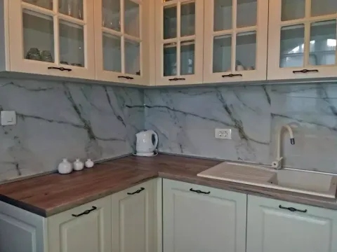 Ugaona kuhinja sa bijelim elementima i radnom površinom u boji drveta. - image 14