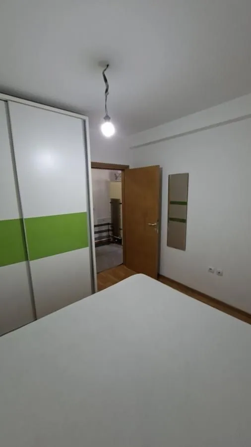 Manja spavaća soba sa krevetom, garderoberom i otvorenim vratima.
