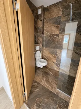 Modern tiled bathroom featuring a wall-hung toilet and a glass partition. - image 6