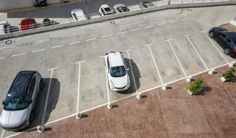 Pogled odozgo na parking prostor sa označenim parking mjestima i parkiranim automobilima. - image 14