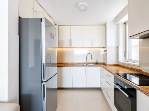 Kuhinja opremljena bijelim elementima, frižiderom i ugrađenom rernom. - image 9