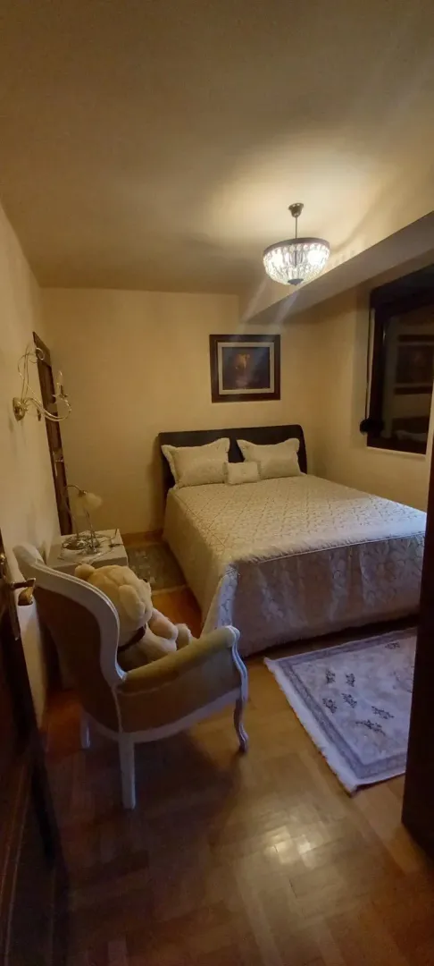 Uredna spavaća soba sa bračnim krevetom i udobnom foteljom.