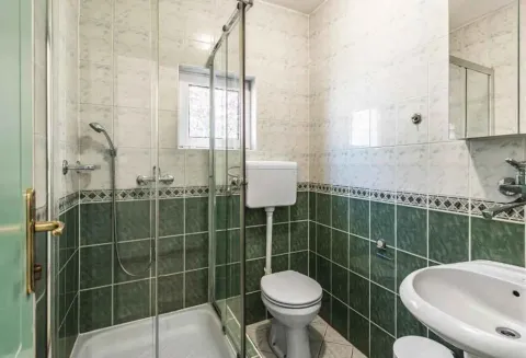 Kupatilo obloženo keramičkim pločicama sa tuš kabinom, WC šoljom i umivaonikom. - image 14