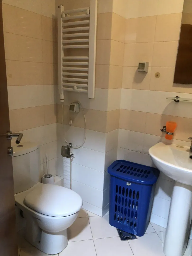 Simple bathroom with light tiles, a sink, and a toilet.