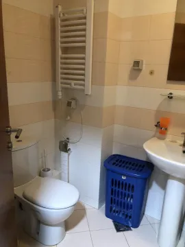 Simple bathroom with light tiles, a sink, and a toilet. - image 7