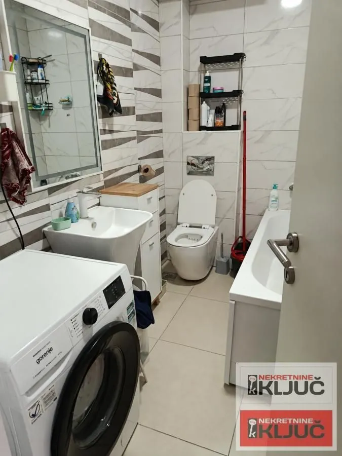 Kupatilo opremljeno umivaonikom, WC šoljom, kadom i veš mašinom.
