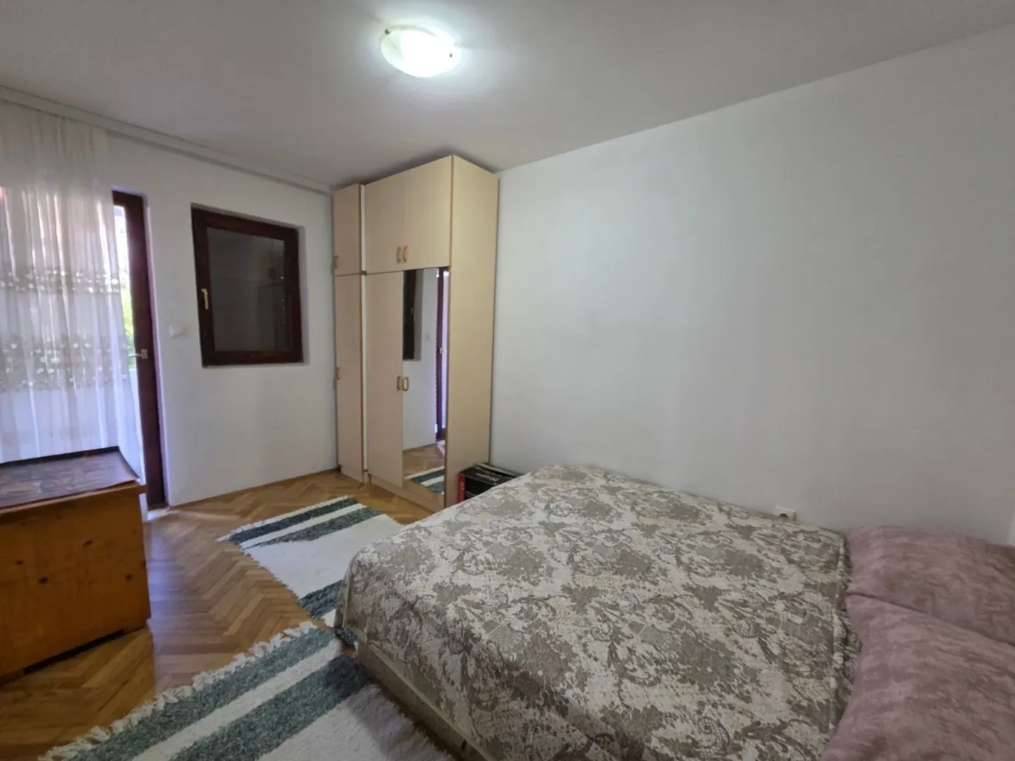 Furnished bedroom with a double bed, wardrobe, and parquet flooring.