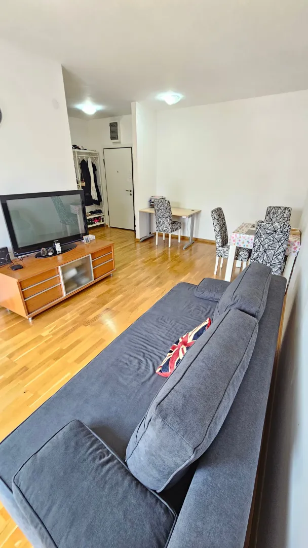Living room with a sofa, TV cabinet, and dining area.