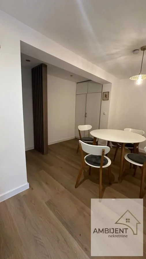 Dining area with a round table and white chairs.