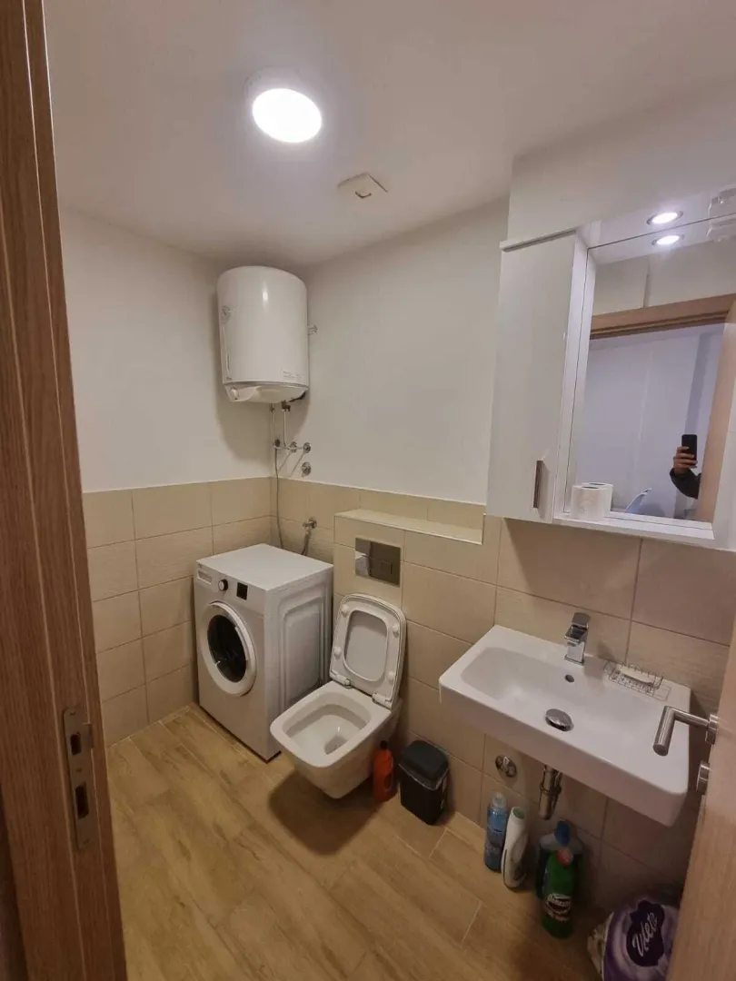 Smaller bathroom with a sink, washing machine, and water heater.